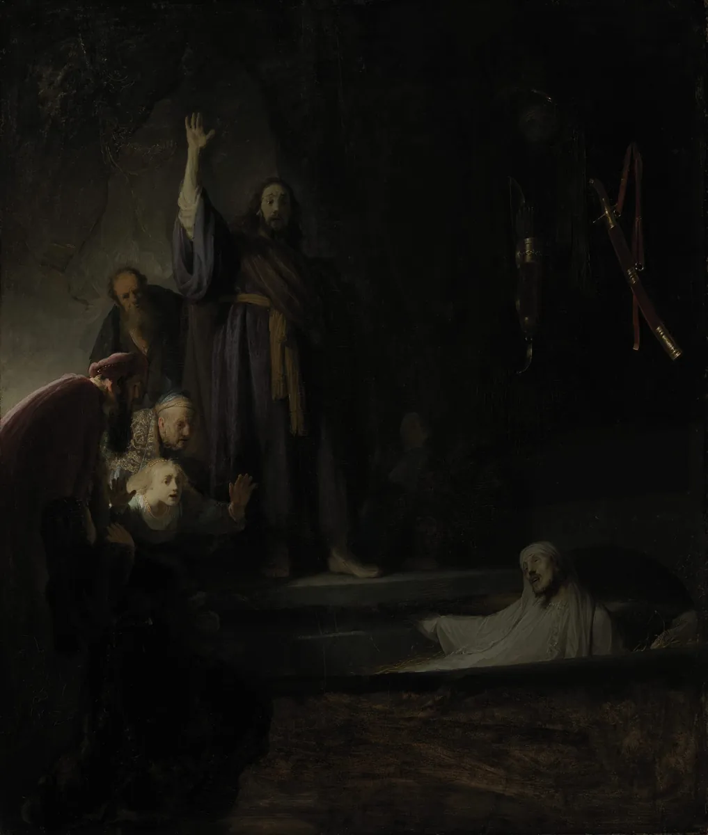 Rembrandt's Raising of Lazarus: in a dark cave a robed figure stands with one hand raised high; below right a pale man in white wrappings rises from a grave, while onlookers at the left lean back with startled faces, and a quiver and sword hang on the rock wall.